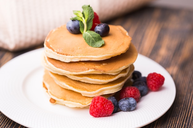 Pfannkuchen mit Blaubeeren und Himbeeren auf Holztisch. Frühstück und traditionelles Essen.