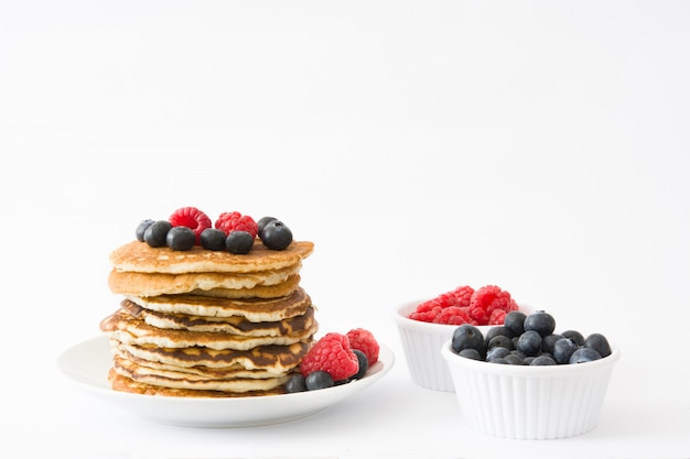 Pfannkuchen mit Blaubeeren und Himbeeren lokalisiert auf weißem Tisch