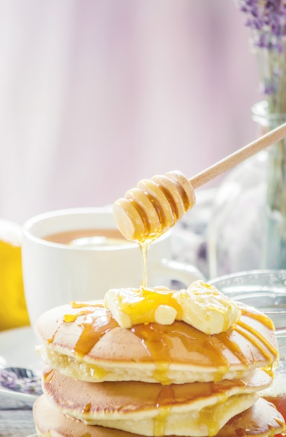 Pfannkuchen mit Butter und Honig und Zitronentee zum Frühstück. selektiver fokus.