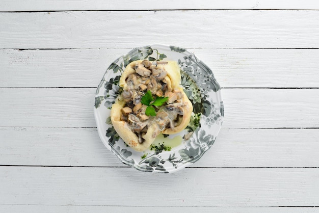 Pfannkuchen mit Champignons, Käse und Sahnesauce Auf einem hölzernen Hintergrund Ansicht von oben Freier Platz für Ihren Text