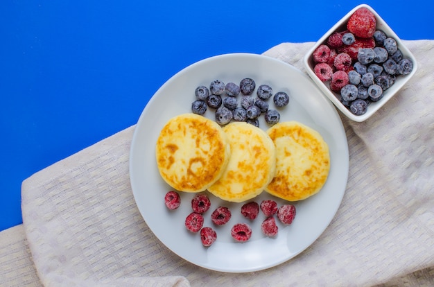 Pfannkuchen mit Erdbeeren, Himbeeren, Blaubeeren auf einer blauen Oberfläche