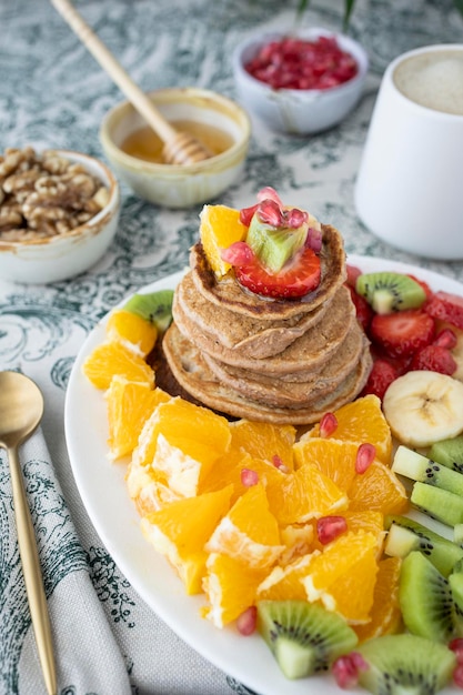 Pfannkuchen mit frischem Obst. Obstsalat mit glutenfreien Pfannkuchen. Gesundes Frühstück voller Vitamine