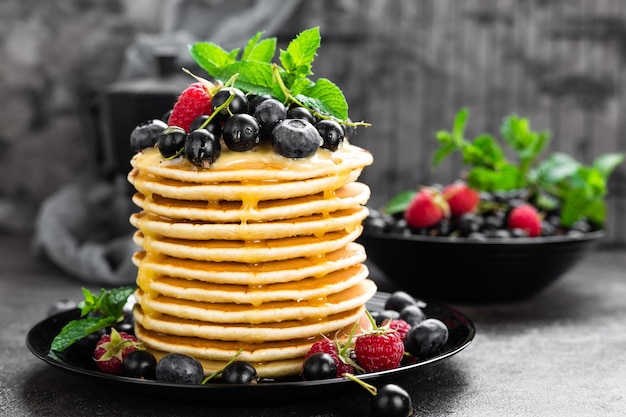 Pfannkuchen mit frischen Beeren Pfannkuchen mit Himbeere, Heidelbeere, schwarzer Johannisbeere und Honig