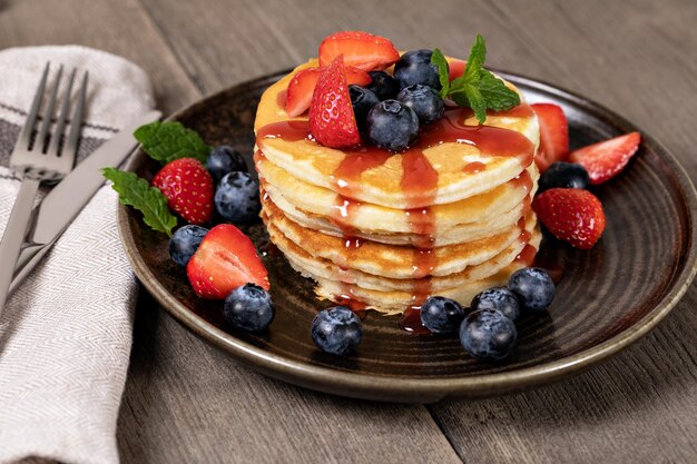 Foto pfannkuchen mit frischen erdbeeren, blaubeeren und sirup