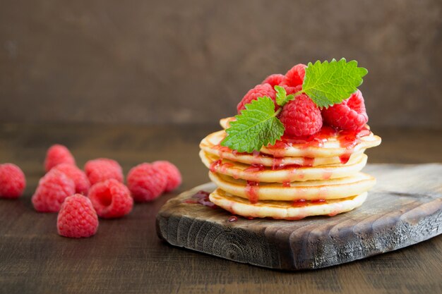 Pfannkuchen mit Himbeeren auf einem dunklen Hintergrund.