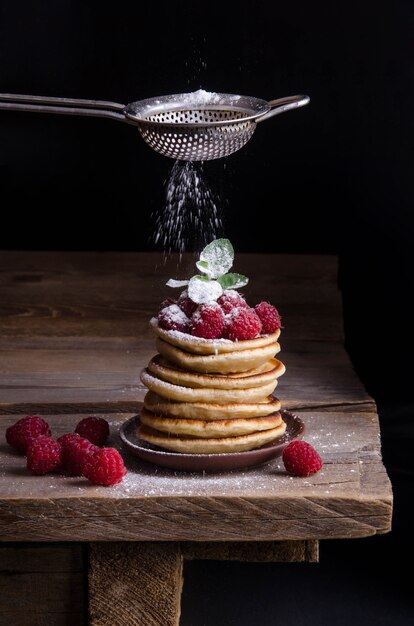 Pfannkuchen mit Himbeeren und Beeren auf schwarzem Hintergrund