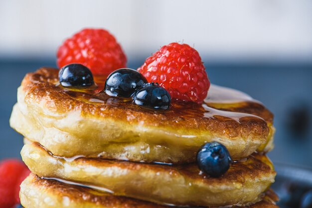 Pfannkuchen mit Honig und Beeren auf einem Holztisch