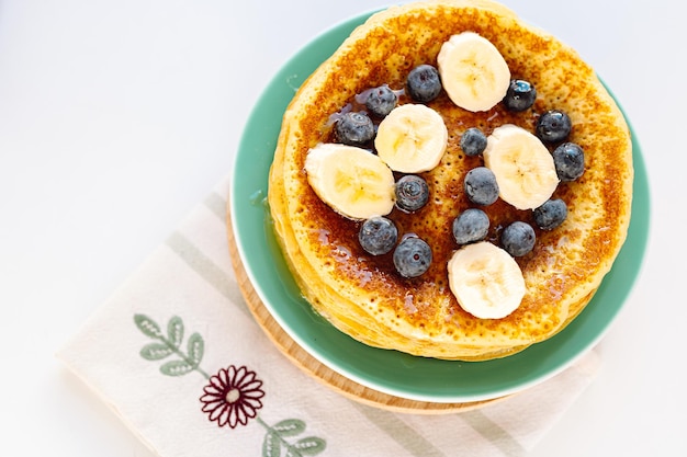 Pfannkuchen mit Honig und frischen Beeren und Früchten zum Frühstück