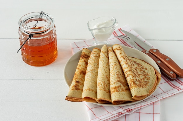 Pfannkuchen mit Honigsirup auf einem weißen Teller. Traditionelle Crpes für Pfannkuchenwoche oder Fastnacht.