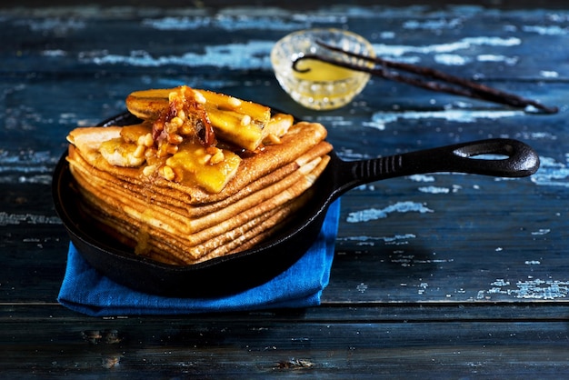 Pfannkuchen mit karamellisierten Bananen und Nüssen in einer gusseisernen Bratpfanne