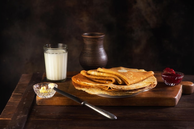 Pfannkuchen mit Marmeladenbutter und Milch in einem Keramiktopf