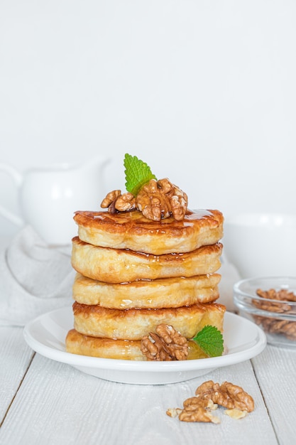 Pfannkuchen mit Nüssen und Honig auf weißem Hintergrund. Seitenansicht, vertikal.