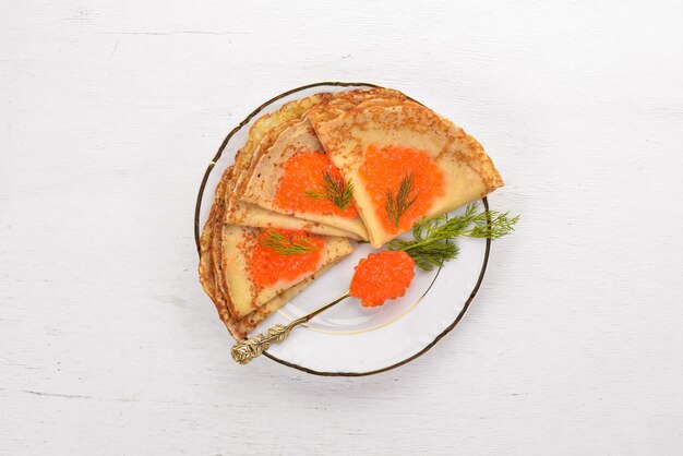 Pfannkuchen mit rotem Kaviar auf einem Teller Auf einem hölzernen Hintergrund Ansicht von oben Freier Platz für Text