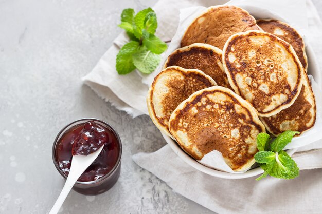 Pfannkuchen mit roter Beerenmarmelade und Minze, hellgrauer Steinhintergrund amerikanische Küche. Frühstück.