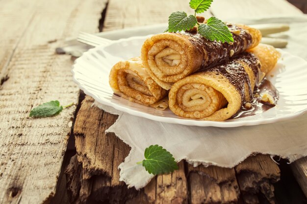 Pfannkuchen mit Schokolade und Tischbesteck auf einem alten Holztisch