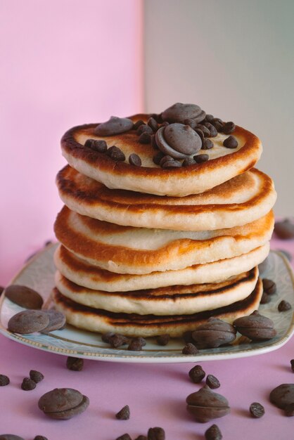 Pfannkuchen schließen mit runden Schokoladenstücken oben und herum auf einer rosa Oberfläche