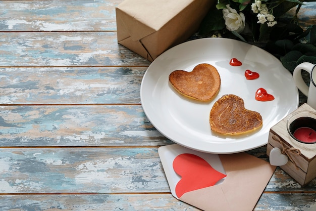 Pfannkuchenherz formte auf weiße Platte, Zusammensetzung für Valentinstag mit Lebensmittel. Platz für Text