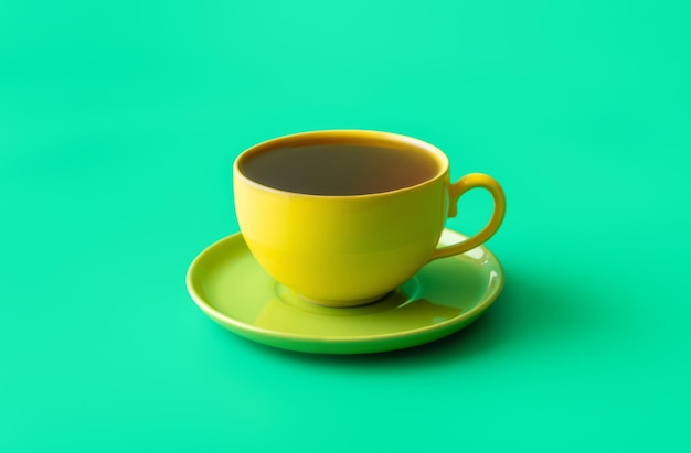 Pfefferminztee in einer gelben Tasse isoliert auf grünem Hintergrund