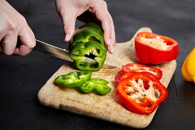 Pfefferschneiden, Handmesser und rot-grün-gelbe Paprika, Holzschneidebrett