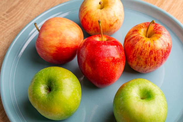 Äpfel auf einer hellblauen Platte auf einem Holztisch