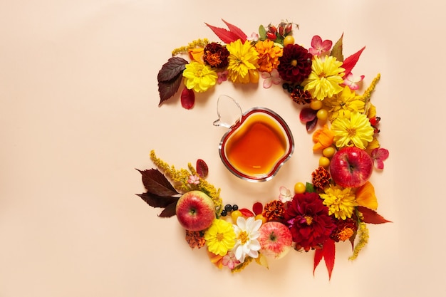 Äpfel, Dahlie, Ringelblumen, Rudbeckiablüten und Honig. Konzept für Rosh Hashanah das jüdische Neujahr. Ansicht von oben, Nahaufnahme, Kopienraum auf pastellfarbenem Hintergrund.