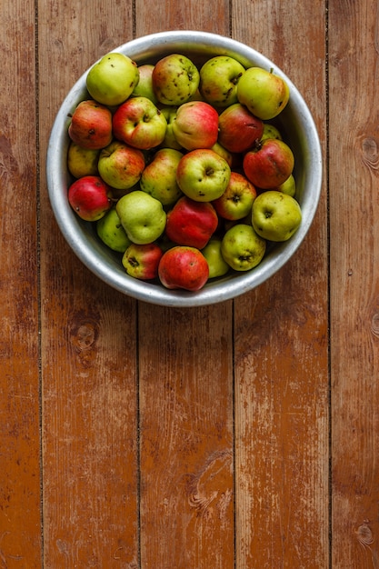 Äpfel im Aluminiumbecken auf Holzboden