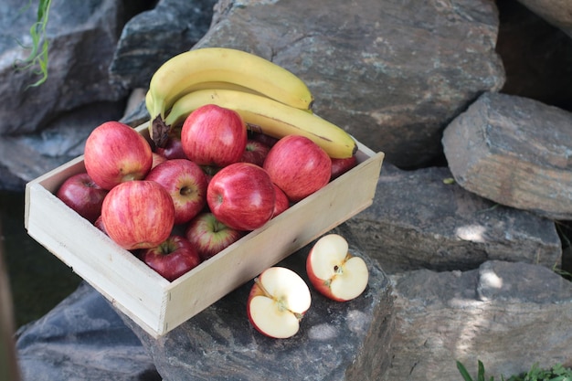 Äpfel und Bananen in einer Kiste im Garten