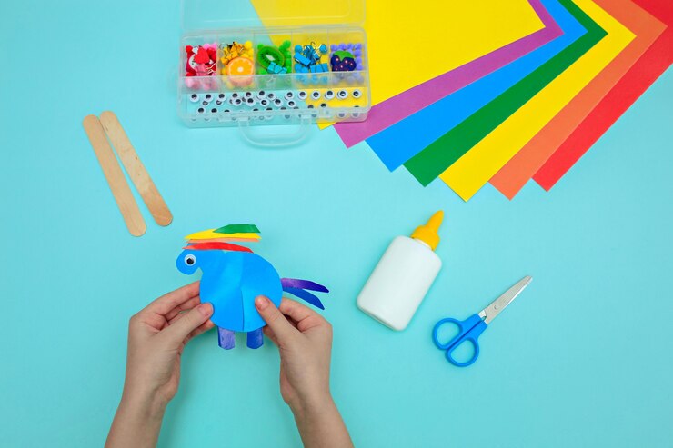 Pferd aus Papier auf einem blauen Tisch, Kinderhände machen Kunsthandwerk von der magischen Farbe des Pferdes
