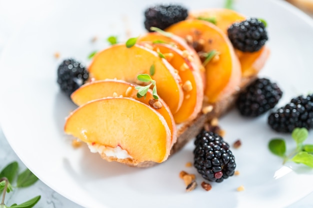 Pfirsich-Ricotta-Toast garniert mit Brombeeren auf einem weißen Teller.