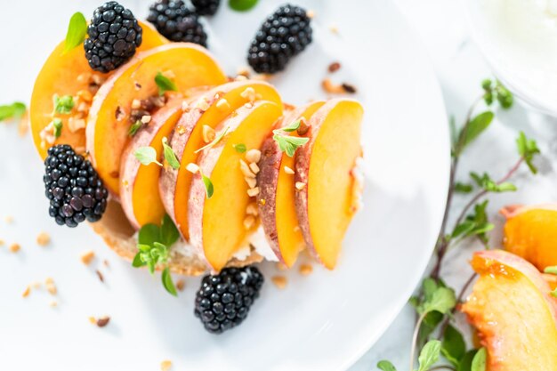 Pfirsich-Ricotta-Toast, garniert mit Brombeeren auf einem weißen Teller.