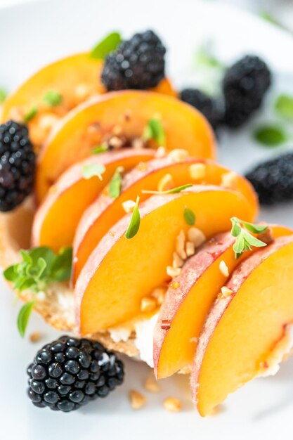 Pfirsich-Ricotta-Toast, garniert mit Brombeeren auf einem weißen Teller.