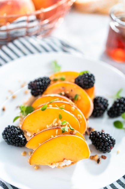 Pfirsich-Ricotta-Toast, garniert mit Brombeeren auf einem weißen Teller.