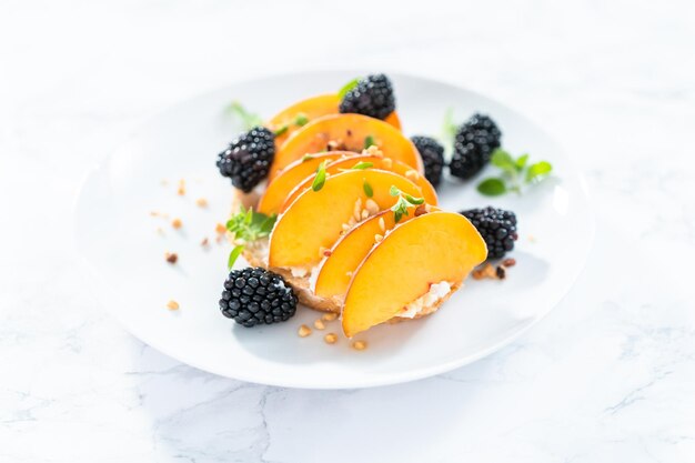 Pfirsich-Ricotta-Toast, garniert mit Brombeeren auf einem weißen Teller.