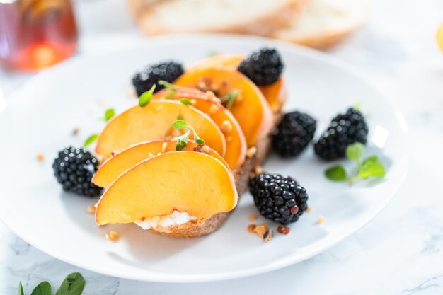 Pfirsich-Ricotta-Toast, garniert mit Brombeeren auf einem weißen Teller.