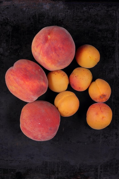 Pfirsiche und Aprikosen auf dunklem Hintergrund Konzept der gesunden vegetarischen Kost Nahaufnahme