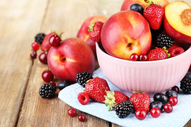 Foto pfirsiche und beeren in der schüssel auf tischnahaufnahme