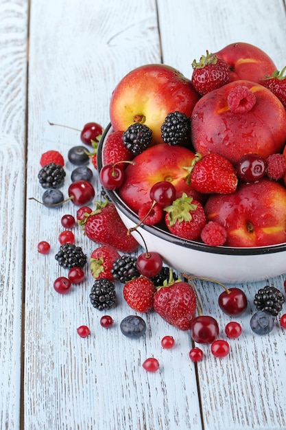 Foto pfirsiche und beeren in schüssel auf dem tisch