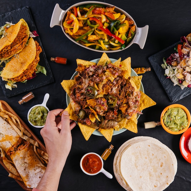 Foto pflanzen sie die hand, die nachos von der platte nimmt