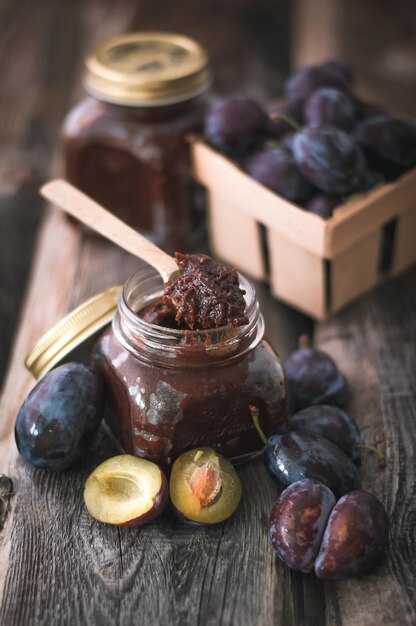 Pflaumenmarmelade im Glas mit Löffel auf Holzhintergrund