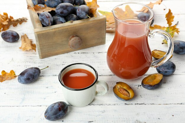 Pflaumensaft im Glas und Becher mit frischen Früchten