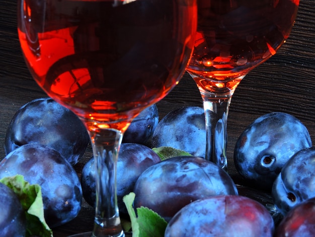 Foto pflaumenwein. helle blaue pflaumen auf einem dunklen hölzernen.