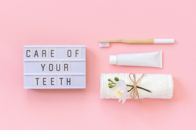 Pflege Ihrer Zähne Text auf Lightbox, natürliche umweltfreundliche Bambusbürste für Zähne, Handtuch, Zahnpastatube