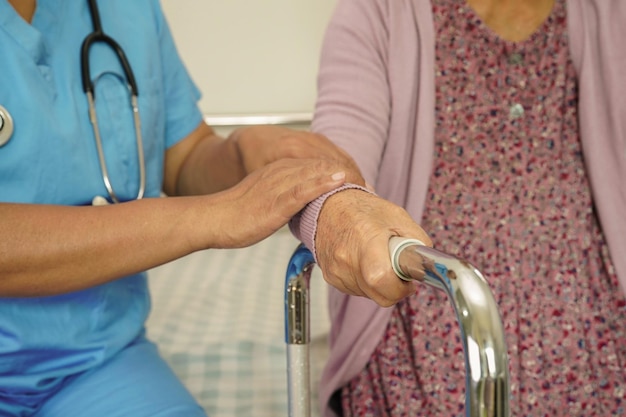 Pflegekraft hilft asiatischen älteren Frauen mit Behinderung beim Gehen mit Rollator im medizinischen Konzept des Pflegekrankenhauses