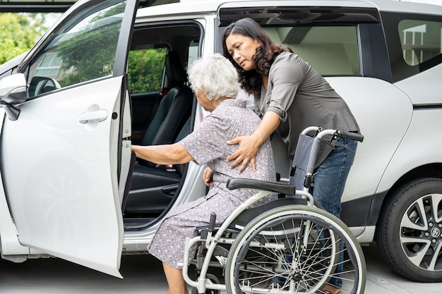 Pflegende tochter hilft und unterstützt asiatische seniorin oder ältere patientin der alten dame, die sich darauf vorbereitet, zu ihrem auto zu gelangen