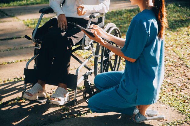 Pflegepersonal spricht mit einer älteren Person, die im Rollstuhl sitzt