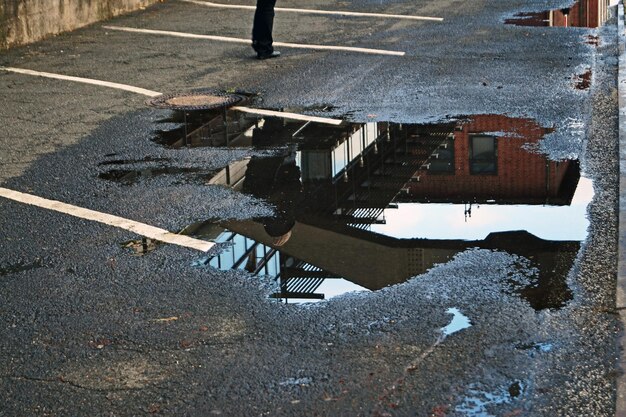 Foto pfütze mit der reflexion eines gebäudes auf der straße