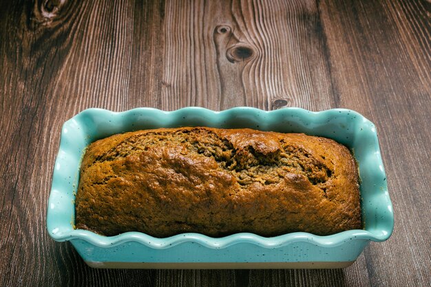 Pfundkuchen in blauer Form auf Holztisch Hausgemachter Bananen-Pfund-Kuchen