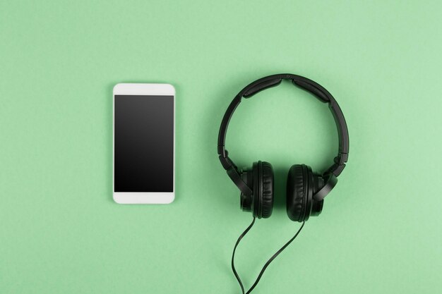 Phablet de concepto de música en línea y auriculares en el fondo verde