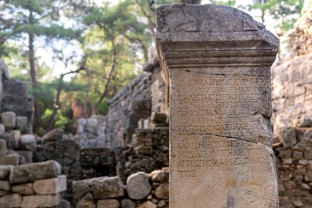 Phaselis, Turquía - 08 de noviembre de 2021: inscripción griega antigua medio borrada en una piedra entre las ruinas de la ciudad antigua
