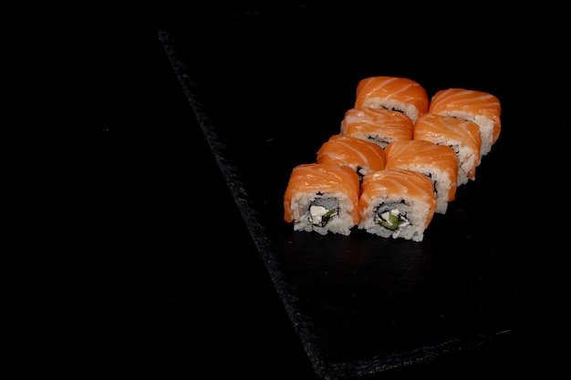 Philadelphia roll com salmão, queijo e pepino em um fundo preto. sushi philadelphia
